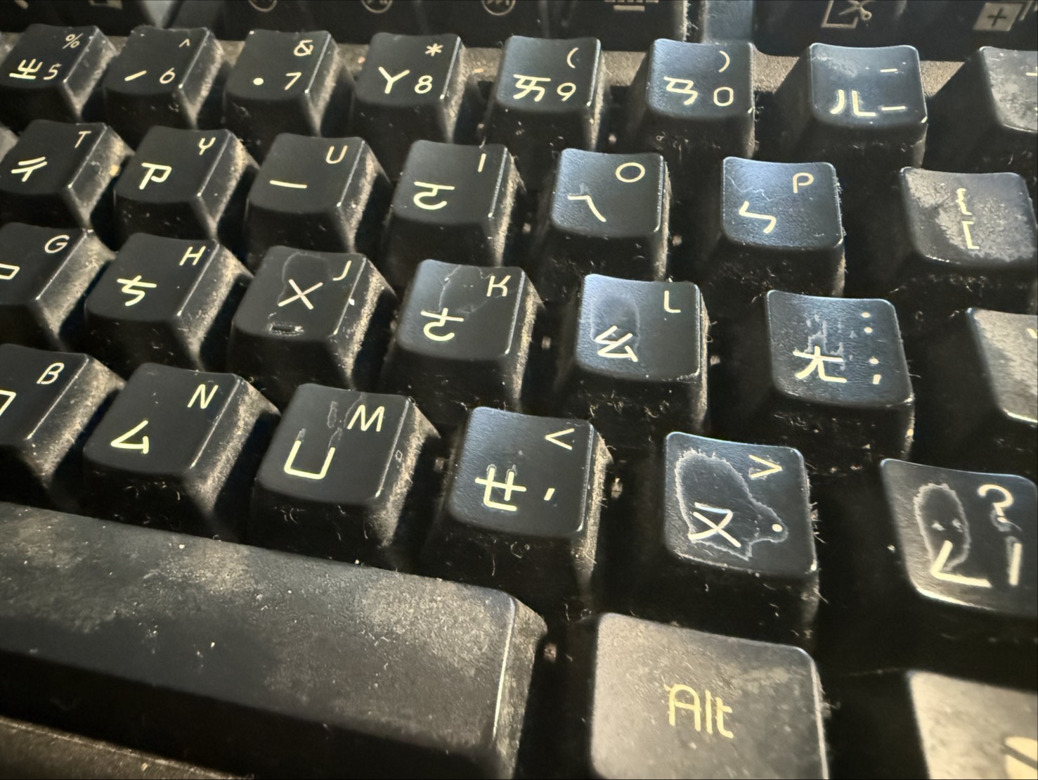 ABS 機械鍵盤鍵帽因長時間遊戲按壓，表面紋理被磨平而產生嚴重反光與「打油」現象的特寫照片